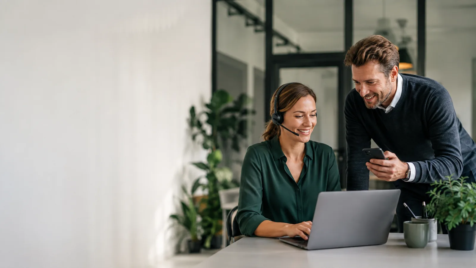 Mitarbeiterin mit Headset und Kollege mit Smartphone bei der Planung moderner Cloud-Telefonie